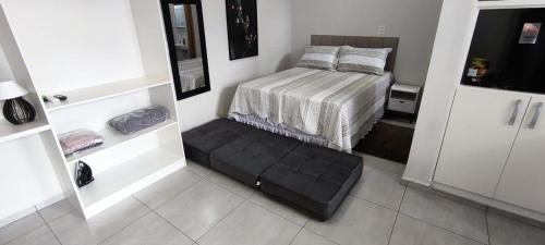 Cette petite chambre comprend un lit avec un pouf noir. dans l'établissement Xavi Studio - Proximo ao Boulevard Shopping, Av Nacoes Unidas e Nuno de Assis., à Bauru