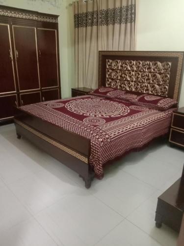 a bedroom with a bed with a red bedspread at Gujrat Guest House in Gujrāt