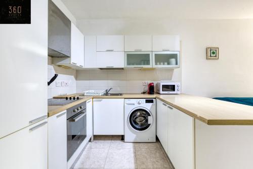 una cucina con armadi bianchi e una lavatrice/asciugatrice di Spacious, central APT in Paceville/St Julians by 360 Estates a San Giuliano