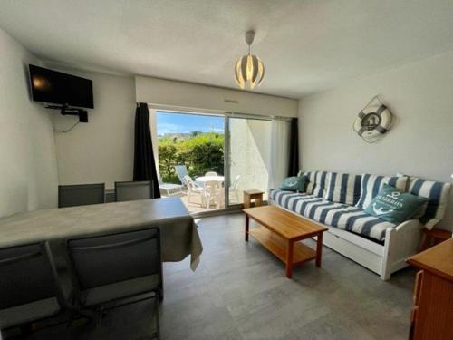 - un salon avec un canapé et une télévision dans l'établissement Quiberon : 3 pièces, 5 pers, piscine, près plage, garage, animaux ok, terrasse/jardin - FR-1-478-85, à Quiberon