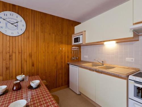une cuisine avec une table et une horloge au mur dans l'établissement Studio 5 pers, centre Brides-les-Bains, balcon, proche thermes et télécabine - FR-1-512-19, à Brides-les-Bains