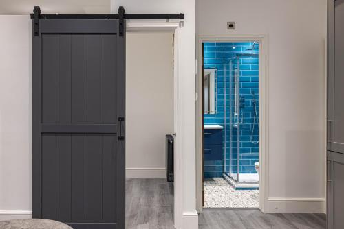 a bathroom with a black sliding door and a blue shower at Edgware road apartments in London