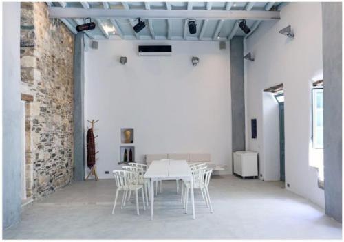 a white table and chairs in a room with a brick wall at La Galerie - Art House Parikia in Parikia