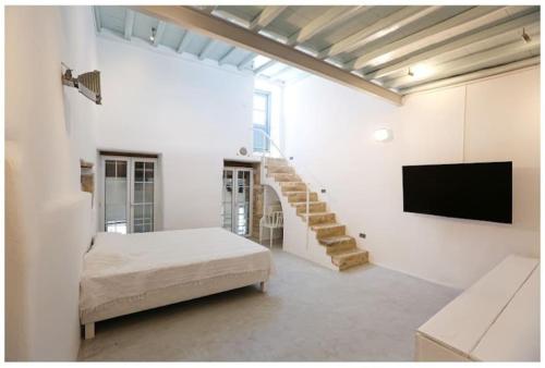 a bedroom with a bed and a tv and a staircase at La Galerie - Art House Parikia in Parikia