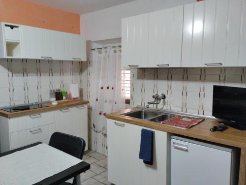 una cocina con armarios blancos y fregadero en Casetta del borgo, en Montelaterone