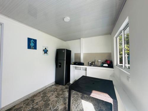 a small kitchen with a black refrigerator and a table at Posada Camp Inn Providencia in Providencia