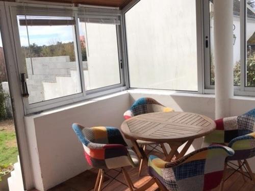 une table et des chaises dans une pièce avec des fenêtres dans l'établissement Maison lumineuse avec jardin à 15 min de la plage et du centre du Palais - FR-1-418-183, au Palais