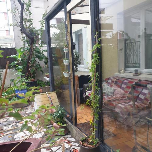 een open deur naar een patio met planten bij La petite maison du 93 in Bagnolet