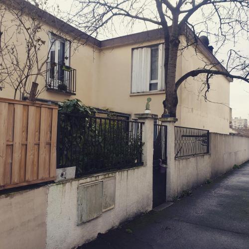 een huis met een hek en een boom op een straat bij La petite maison du 93 in Bagnolet