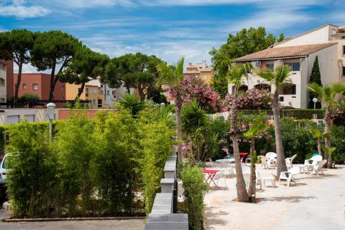 a garden with plants and trees and buildings at Appart'Hôtel Agathea in Cap d'Agde