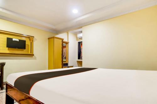 um quarto com uma cama grande e uma televisão de ecrã plano em Super Collection O Hotel Adithya Central em Elūru