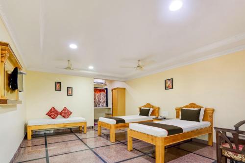 a room with two beds and two chairs at Super Collection O Hotel Adithya Central in Elūru