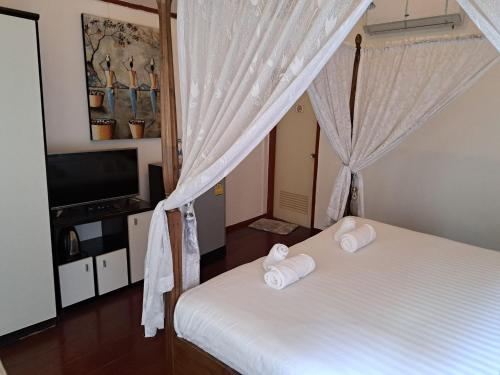 a bedroom with a bed with white sheets and a television at Stay 7 Jomtien Resort in Jomtien Beach