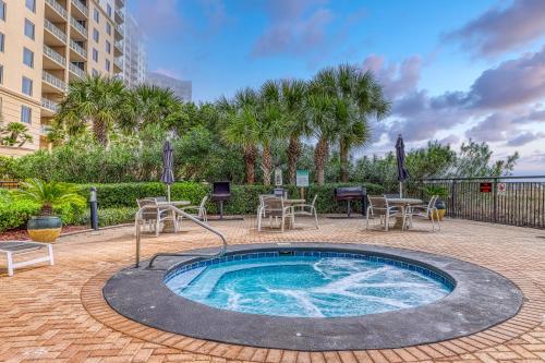 a hot tub with tables and chairs and palm trees at Palacio Condominiums II in Perdido Key