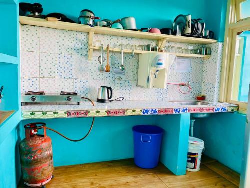 a blue kitchen with a counter with dishes on it at Jagatram Niwas in Dharamshala