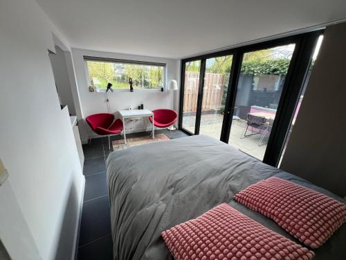 a bedroom with a bed and a desk with red chairs at Naar Ineke in Doesburg