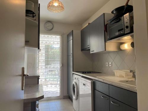 une cuisine avec une machine à laver et une fenêtre dans l'établissement Appartement 2P à Juan les Pins : emplacement idéal, parking, terrasses, proche plage et commerces - FR-1-252-188, à Antibes