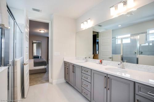 La salle de bains est pourvue d'un lavabo et d'un grand miroir. dans l'établissement Encore Resort 6 Bedroom Vacation Home with Pool 1913, à Orlando