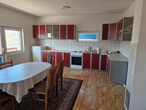 uma cozinha com armários vermelhos e uma mesa com cadeiras em Apartman Vujovic em Zlatište