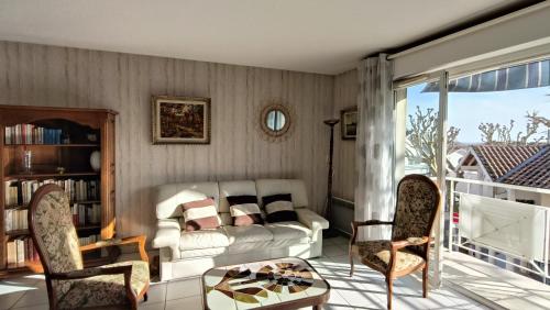 un salon avec un canapé, une table et des chaises dans l'établissement Appartement Le Broustey la plage au bout de la rue, à Andernos-les-Bains
