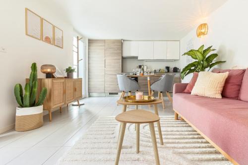 a living room with a pink couch and a kitchen at Bohème - Home cinéma, Terrasse, Parking & Proche Lac in Estavayer-le-Lac
