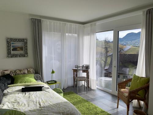 een slaapkamer met een bed en een groot raam bij Chez Svanette B&B Villa Sonnglück in Zullwil