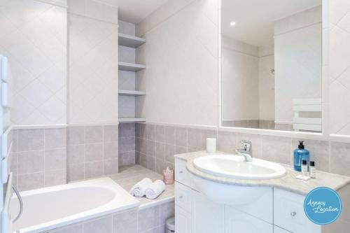 ein weißes Badezimmer mit einer Badewanne und einem Waschbecken in der Unterkunft L'Éclat D'annecy - Appartement Avec Vue Lac in Annecy