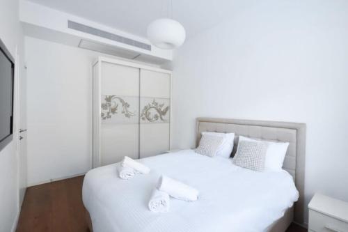- une chambre blanche avec un lit blanc et un canapé dans l'établissement Cozy 2BR in Hayarkon 96 by HolyGuest, à Tel Aviv