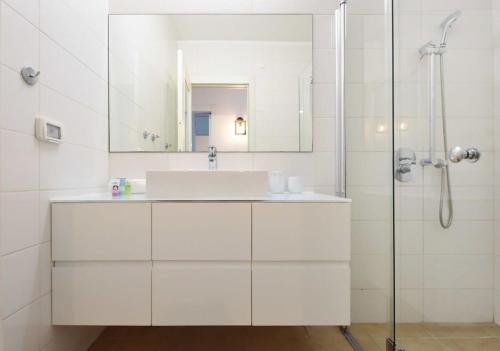 La salle de bains blanche est pourvue d'un lavabo et d'une douche. dans l'établissement Cozy 2BR in Hayarkon 96 by HolyGuest, à Tel Aviv