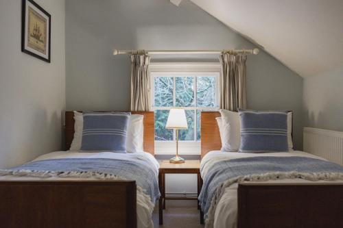 two beds in a room with a window at Bears Cottage in Wood Norton