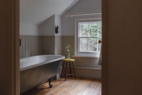 baño con bañera grande y ventana en Bears Cottage, en Wood Norton