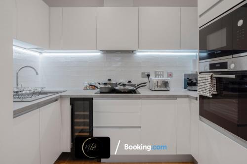 cocina blanca con fregadero y fogones en Stylish City Centre Escape, Serviced Accommodation in Birmingham Suitable For Families, Visitors & Contractors, Wi-Fi, Games & Netflix - By Noor Luxury Accommodations, en Birmingham