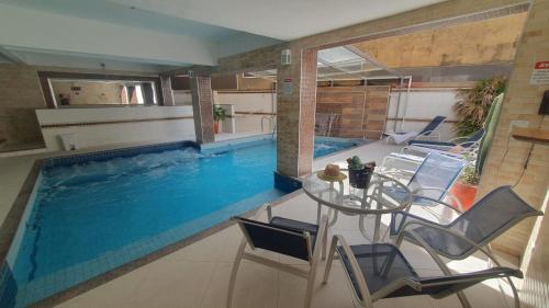 a swimming pool with a table and chairs in a room at Presidente Hotel in Poços de Caldas