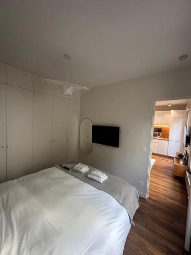 - une chambre avec un grand lit blanc et une télévision à écran plat dans l'établissement Cosy Apt 4P-porte maillot -palais des congrés, à Paris