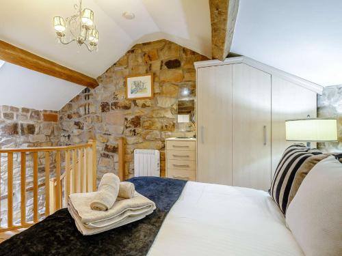 1 dormitorio con cama y pared de piedra en 1 bed in Meerbrook 87507 en Meerbrook