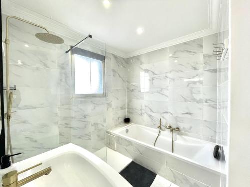 une salle de bain blanche avec une baignoire et un lavabo dans l'établissement Vezelay 3 luxury 3 bedrooms, by Welcome to Cannes, à Cannes