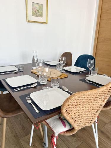 - une table à manger avec des chaises, des assiettes et des verres à vin dans l'établissement Le Surcouf - Terrasse privative, à La Rochelle