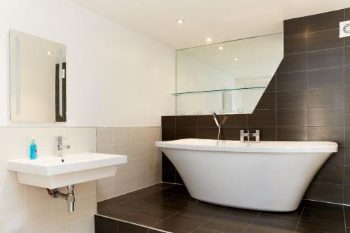 a bathroom with a sink and a tub and a mirror at Finest Retreats - Nether Burrows Farm in Ashbourne