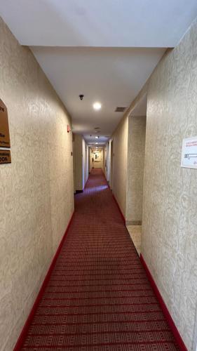 a long corridor with a red carpet in a hallway at Crescent Hotel in Long Island City