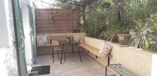une terrasse avec un banc, une table et des chaises dans l'établissement Les figues, à Hyères