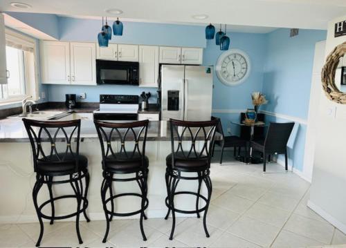 a kitchen with three bar stools and a refrigerator at Ocean Front in Cocoa Beach in Cocoa Beach