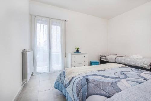 a white bedroom with two beds and a window at Minimalist Oasis - City life & Hesperia Hospital in Modena