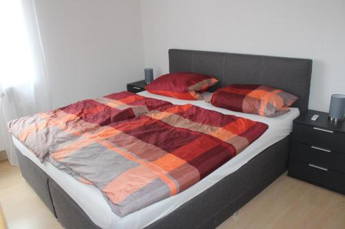 een bed met een rode en oranje deken en kussens bij NEU! Ferienwohnung Nickel in Ahausen