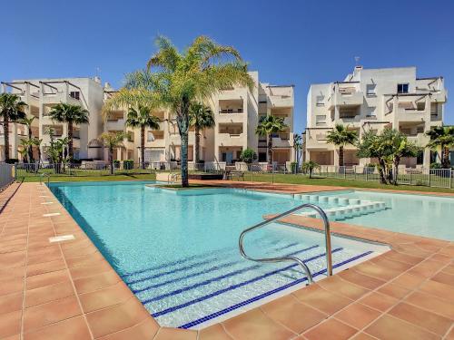 a swimming pool in a apartment with palm trees and buildings at Cosy Top-Floor Sunny Apartment with Balcony, Stunning Golf Resort Views,Proximity to Swimming Pool and Kids Playground, Only 20min to the Beach in Roldán