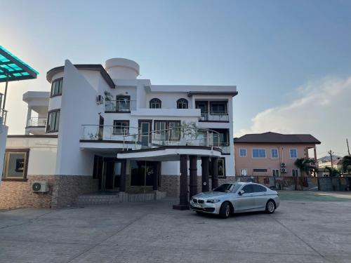 een witte auto geparkeerd voor een gebouw bij JD Hotel And Bar. in Accra