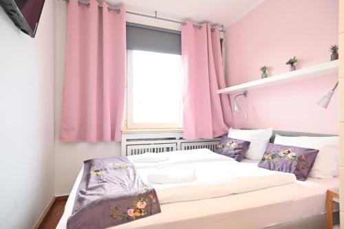 2 camas en una habitación con cortinas rosas en Self check in City HoStel Nordstern, en Essen