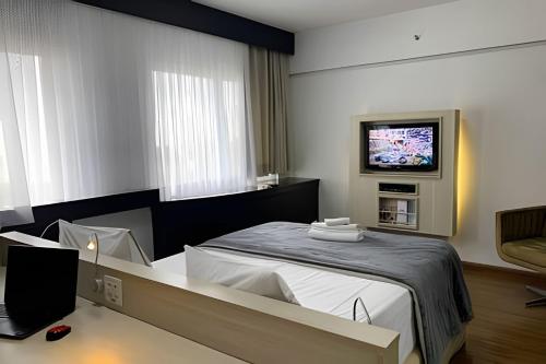 um quarto com uma cama e uma televisão na parede em Get a Flat 1203 Bela Vista Excelente Localização SP em São Paulo