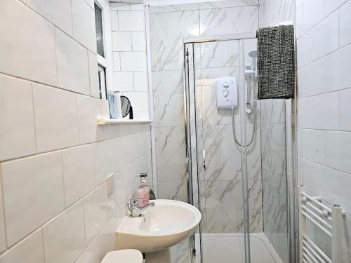 een witte badkamer met een wastafel en een douche bij Modern & Cosy 1 bedroom flat in Bridgend
