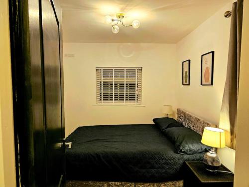 a bedroom with a black bed and a window at Modern & Cosy 1 bedroom flat in Bridgend