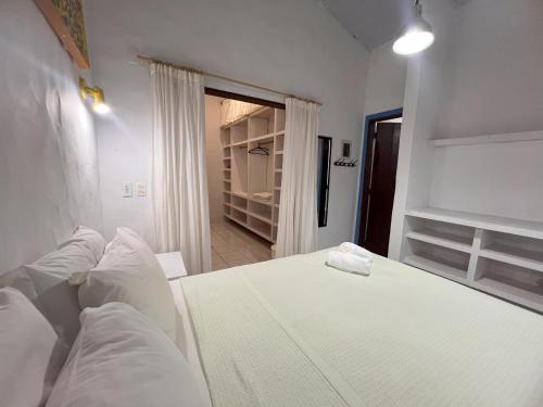 ein weißes Bett mit weißen Kissen im Schlafzimmer in der Unterkunft Zil Hospeda in Pipa